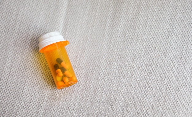 A bottle of pills with a white cap on it