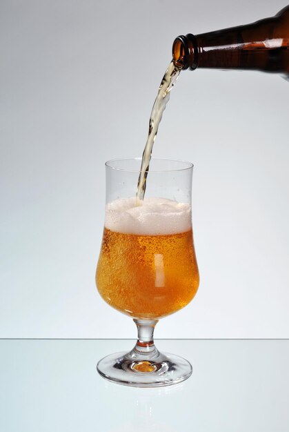 Bottle pouring drink in glass against white background