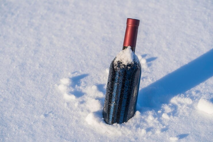 雪と白い背景のベッドに赤ワインのボトル