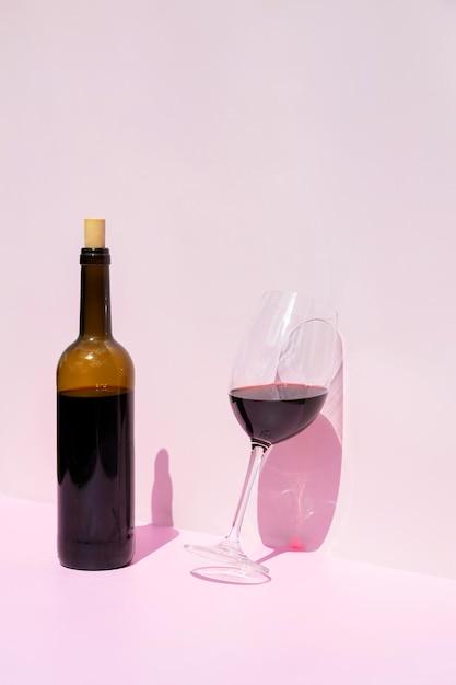 은 와인 한 병 과 그  에 있는 채워진 유리잔 이 빛 에 있는 분홍색 배경 에 있는 텍스트 를 위한 장소