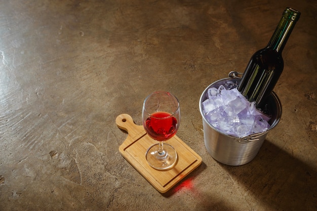 Bottle of red wine  in an ice bucket and a glass of red wine