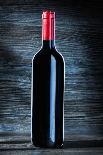 Bottle of red wine on vintage wood background