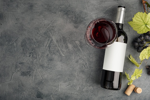 Bottle of red wine with label. Glass of wine and grape. Wine bottle mockup. Top view.