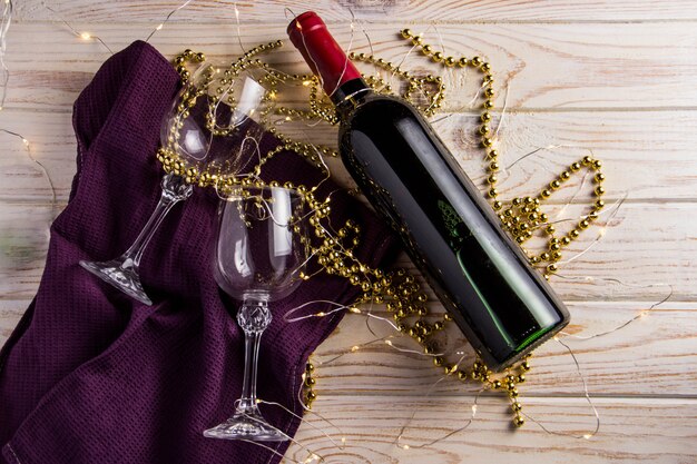 Photo a bottle of red wine with two glasses on a wooden floor