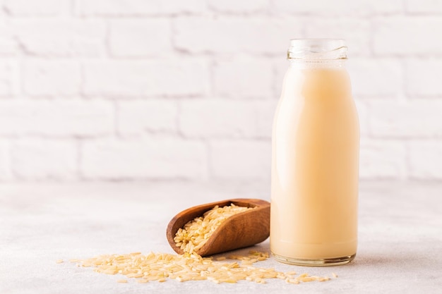 A bottle of rice milk and rice on a light background.