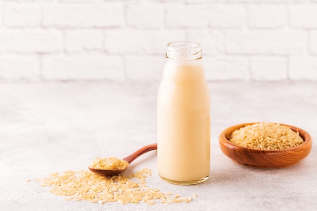 A bottle of rice milk and rice on a light background.