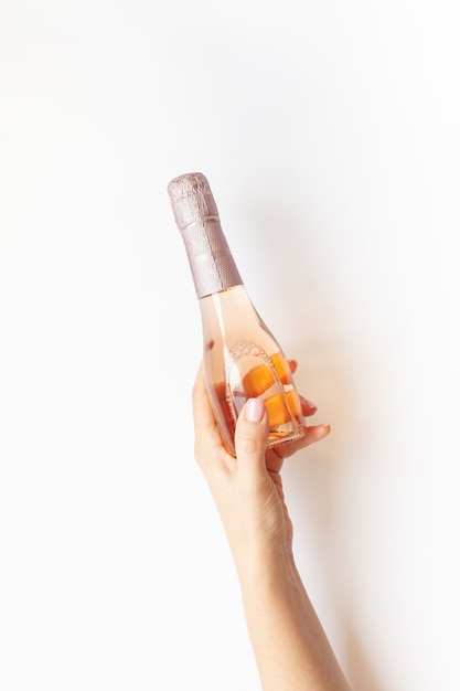 Bottle of rose champagne wine in woman hand