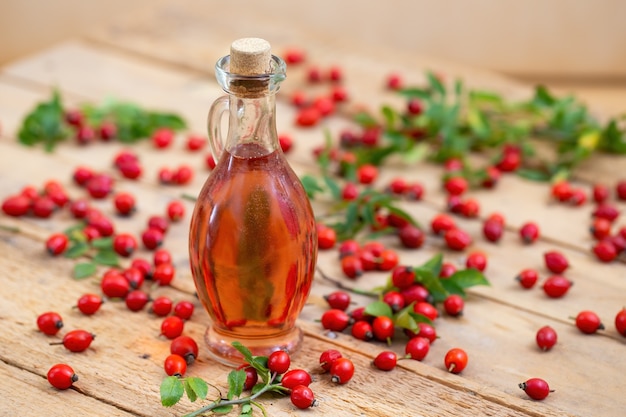 A bottle of rose hip oil with red berries in background.