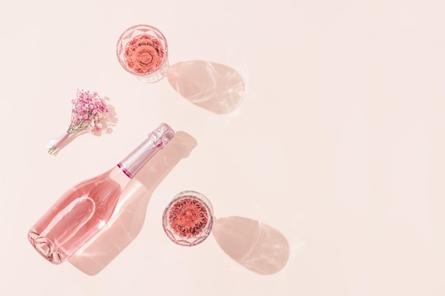 Bottle of rose wine two glasses with drink bouquet of flowers in sunlight Summer romance concept