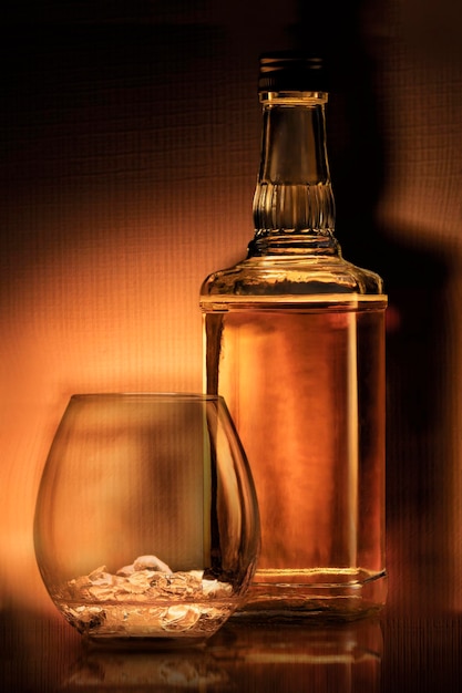 A bottle of rum  golden whiskey or liqueur  a glass of bourbon has a beautiful dark background elite...