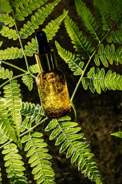 Photo a bottle of serum on a fern