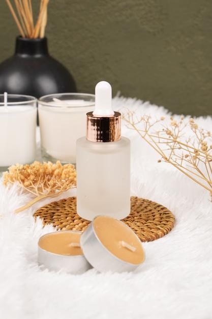 a bottle of serum oil sits on a table with candles and a black and white bottle of perfume