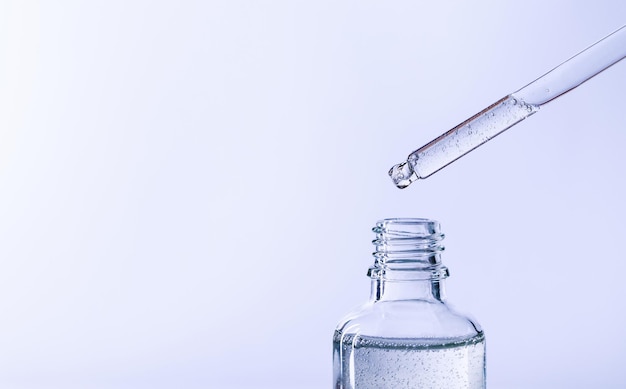 Bottle of serum with a pipette on a light background