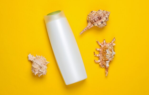 Bottle of shampoo with shells on a yellow