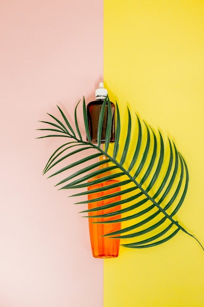 Bottle sunblock on bright square yellow and pink wall. Top view, flat lay, minimalism, copy space.