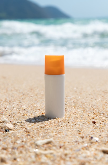 Foto bottiglia di crema solare sulla spiaggia di sabbia sul mare