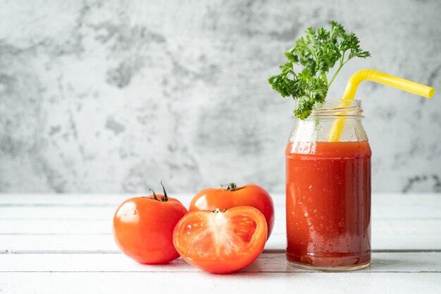 Bottle of tomato juice and fresh tomatoes on wooden table. copy space