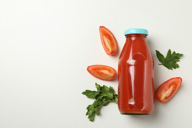 Bottle of tomato juice and tomato slices on white