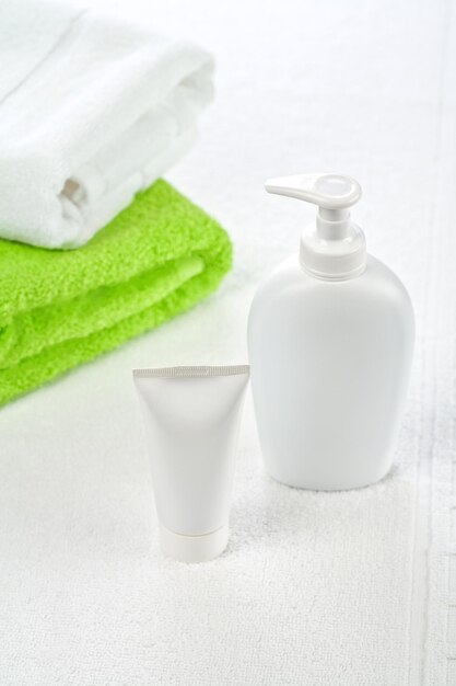 Bottle tube and towels on white background