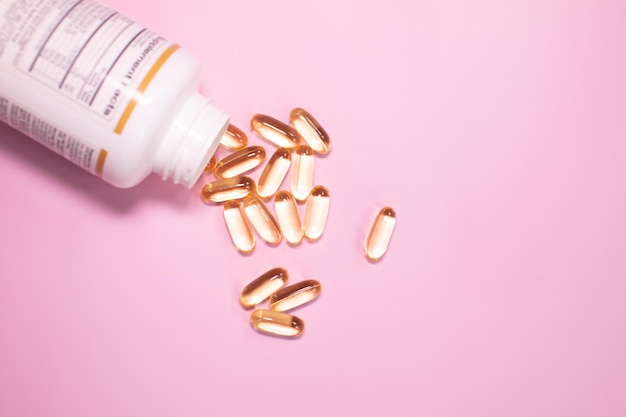 A bottle of vitamins is poured into a pink background.