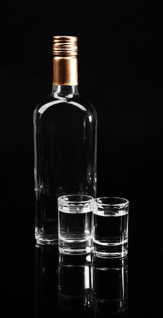Bottle of vodka and glasses isolated on black
