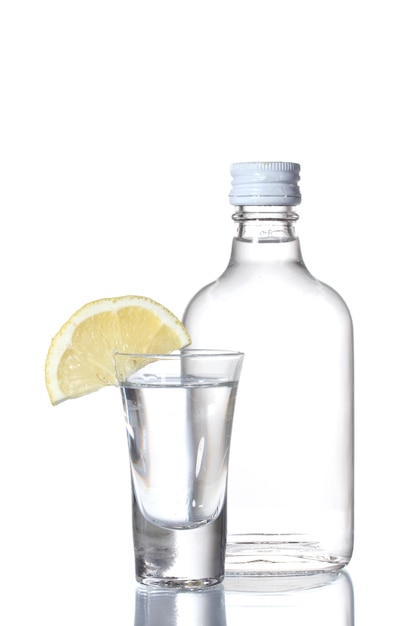 Bottle of vodka and wineglass with lemon isolated on white