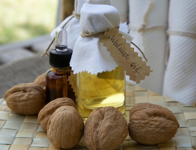 bottle of walnut oil on the woven surface. walnuts in the background