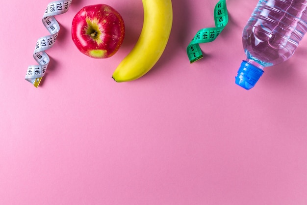 A bottle of water, an apple, a banana and a measuring tape. Sport and diet concept. Sports and healthy lifestyle. Copyspace background