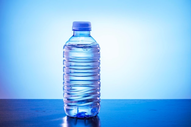 Photo bottle of water bottled in a container of recycled plastic on blue background drink water