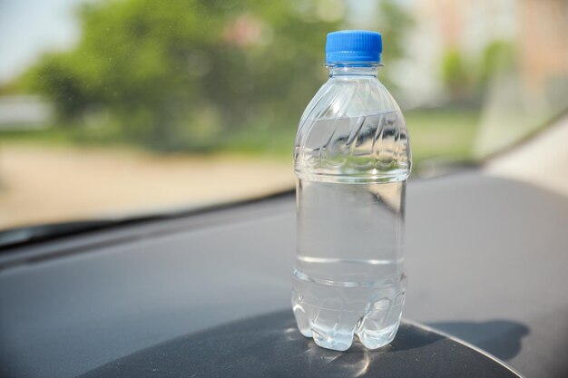 A bottle of water sits on the dashboard of a car.