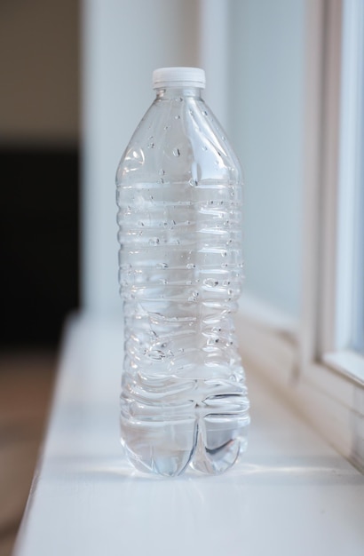 A bottle of water sits on a window sill.