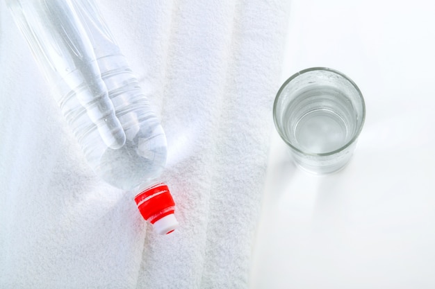 Bottle of water with glass and towel