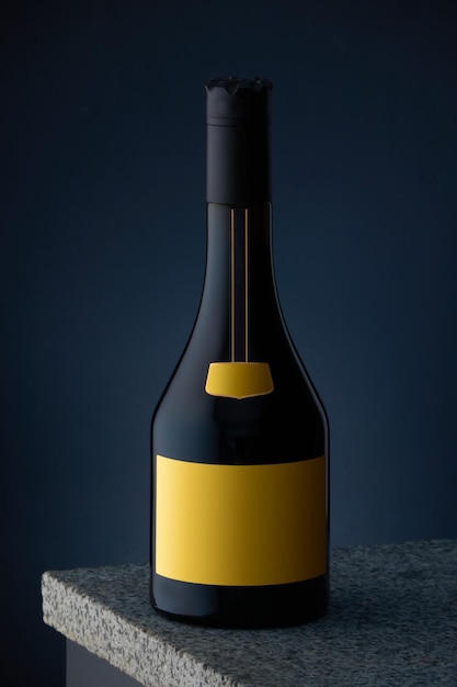 Bottle of whiskey cognac brandy with yellow label on marble surface and dark blue background