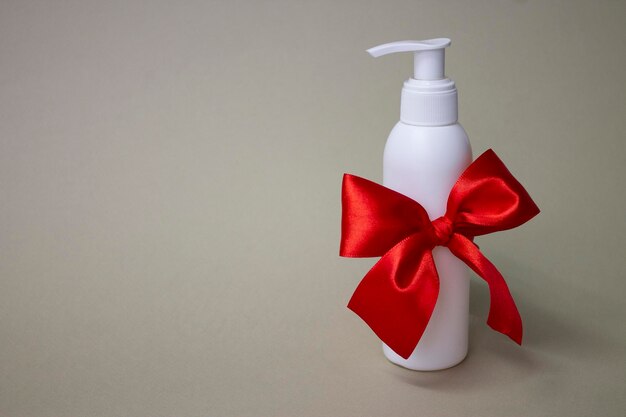 A bottle of white lotion with a red ribbon on it.