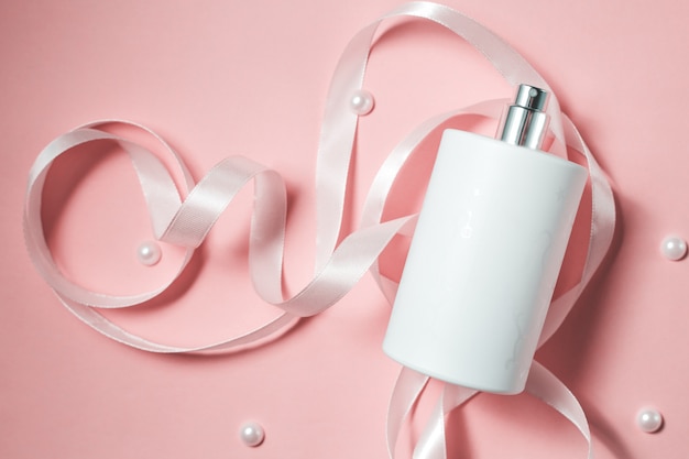 Bottle of white perfume on pink background