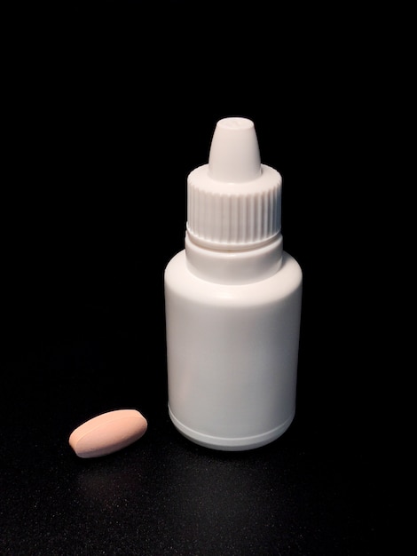 Bottle of white and a tablet on black table