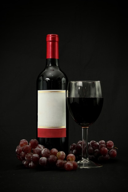 Bottle of wine accompanied by a glass, bunches of grapes bunches