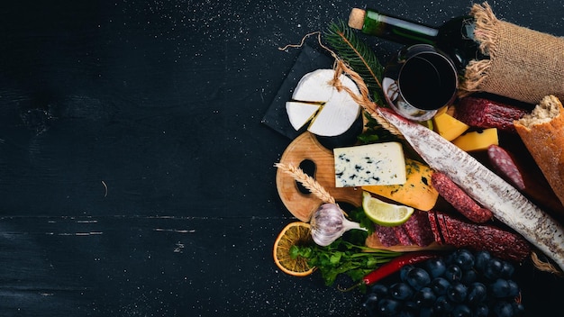 A bottle of wine cheeses and traditional sausages on a wooden background Brie cheese blue cheese gorgonzola fuete salami Free space for text Top view