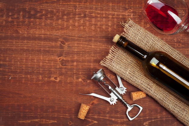 Foto bottiglia di vino e sughero e cavatappi sulla tavola di legno