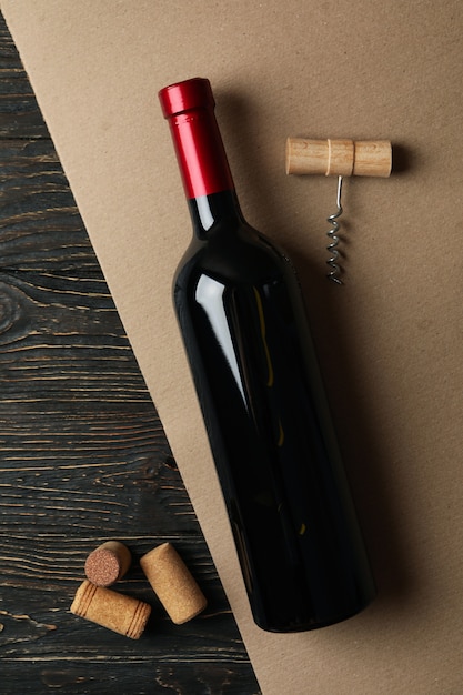 Bottle of wine, corks and corkscrew on two tone background