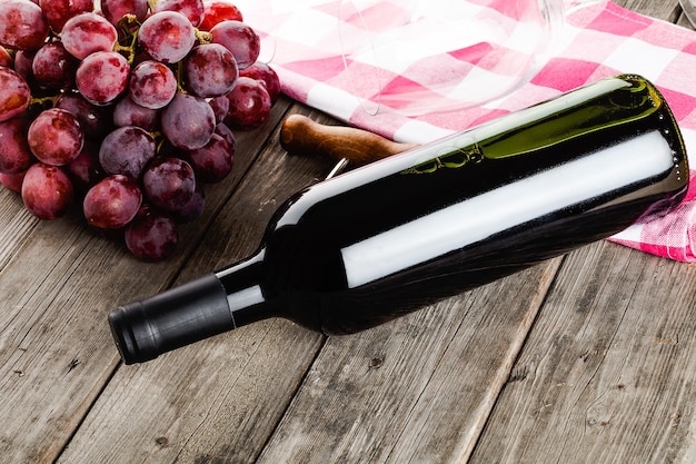 Bottle of wine corkscrew amd grapes on wooden table