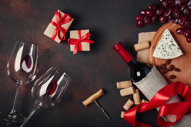 Bottle of wine, gift box, red grapes, almonds, corkscrew and corks,  top view