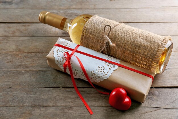 나무 배경에 있는 상자에 있는 와인 한 병과 선물