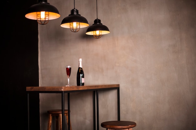 A bottle of wine and a glass stand on a wooden table in the restaurant hall