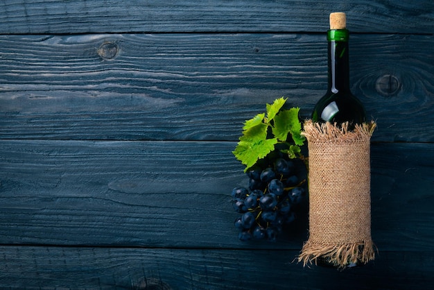 A bottle of wine and grapes. On a wooden background. Top view. Free space for your text.