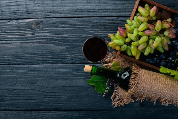 A bottle of wine and grapes On a wooden background Top view Free space for your text