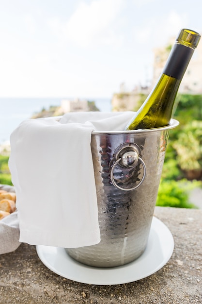 A bottle of wine in an ice bucket in the open area of restaurant