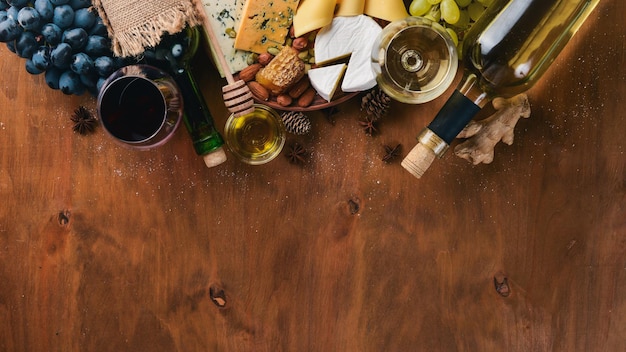나무 테이블에 있는 와인 한 병, 다양한 치즈 꿀 견과류, 향신료 상위 뷰 텍스트를 위한 여유 공간