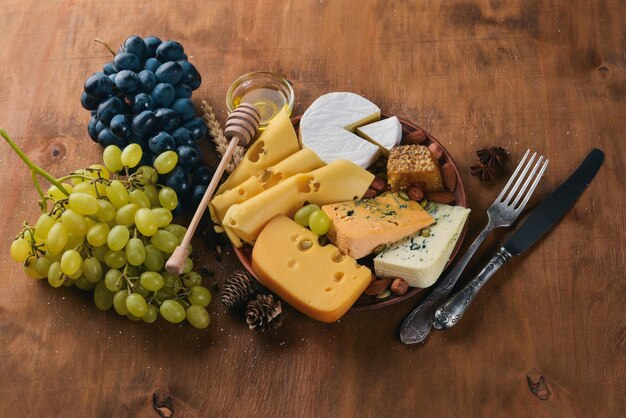 나무 테이블에 있는 와인 한 병, 다양한 치즈 꿀 견과류, 향신료 상위 뷰 텍스트를 위한 여유 공간