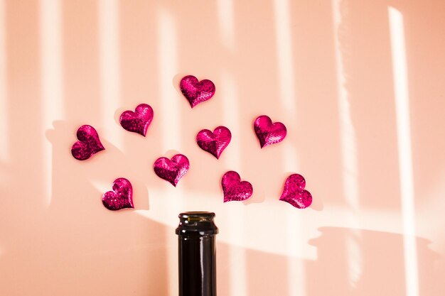 Bottle of wine and pink hearts over morning shadow overlay Valentines day beginning concept